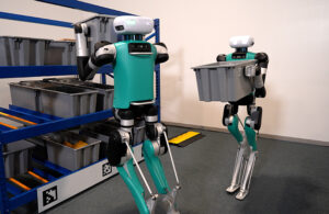 agility humanoid robots handling totes in a warehouse.