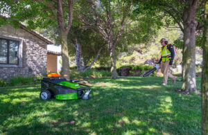 Electric Sheep Robotics' autonomous mower working alongside a landscaping employee.
