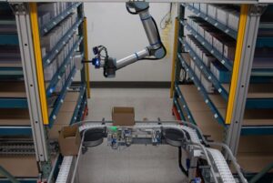 image of a UR robot hanging from the ceiling and pulling boxes from warehouse shelves.