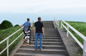 a person wearing a lifeward exoskeleton walking up the stairs.